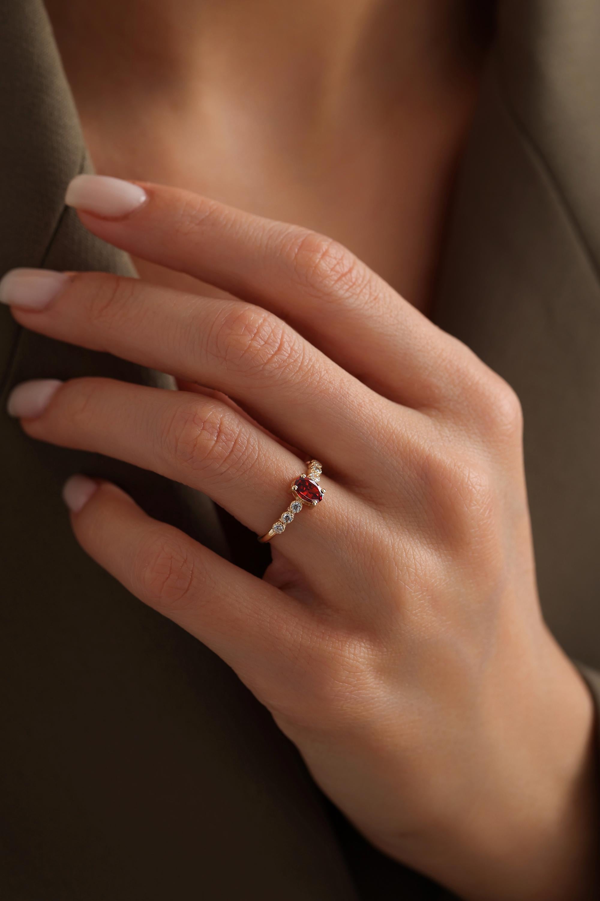 A close-up of a person's hand wearing a gold ring with a red gemstone.