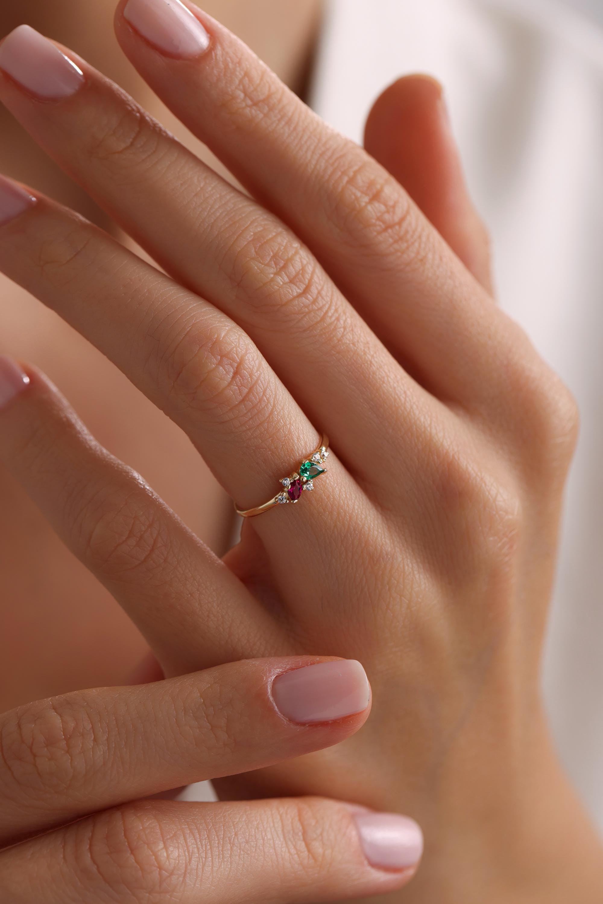 May include: A gold ring with a cluster of small diamonds, a red gemstone, and a green gemstone.