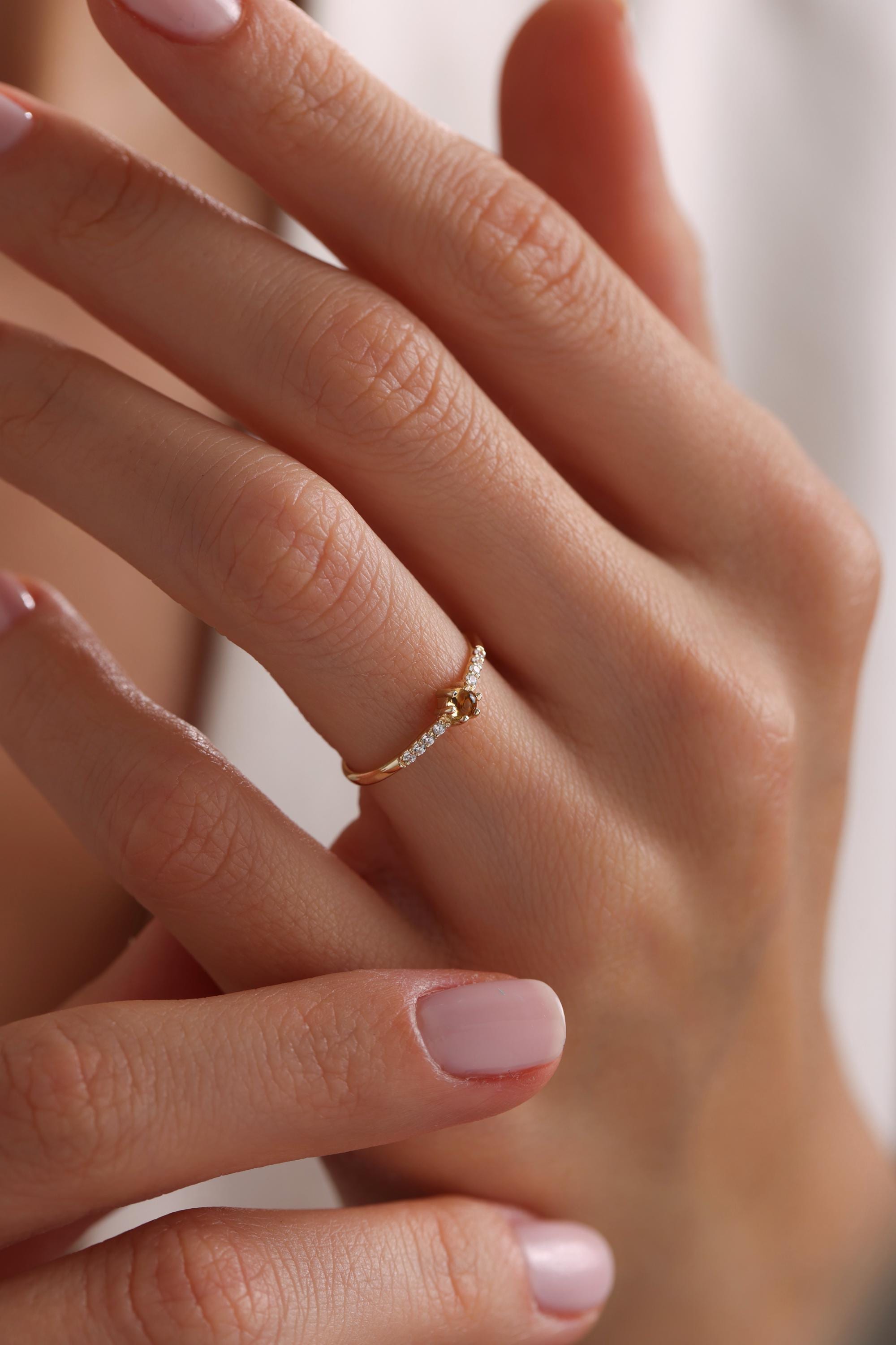 May include: A gold ring with a small brown gemstone and a row of small white gemstones on the band.