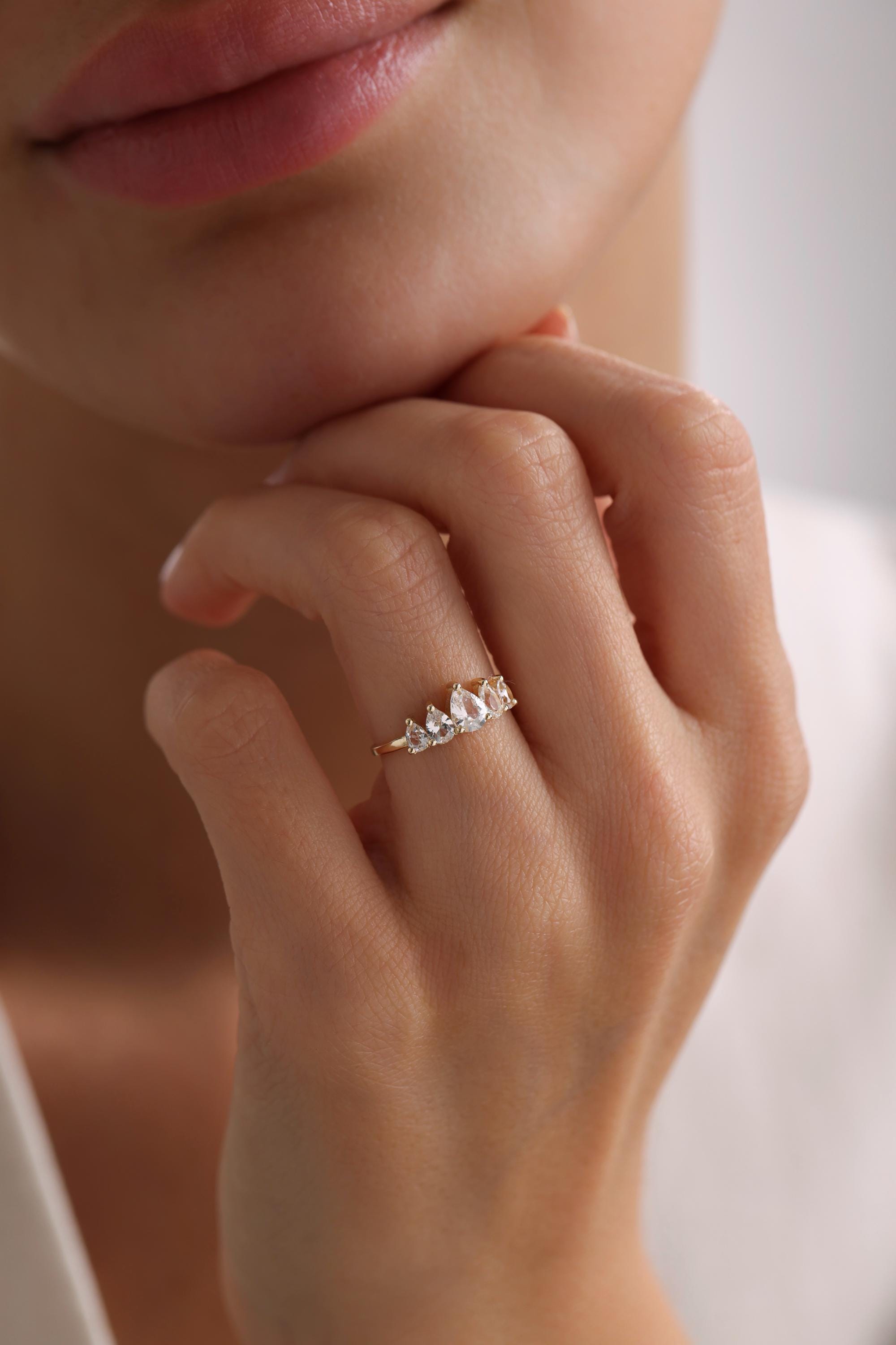May include: A gold band ring with a row of pear-shaped clear gemstones