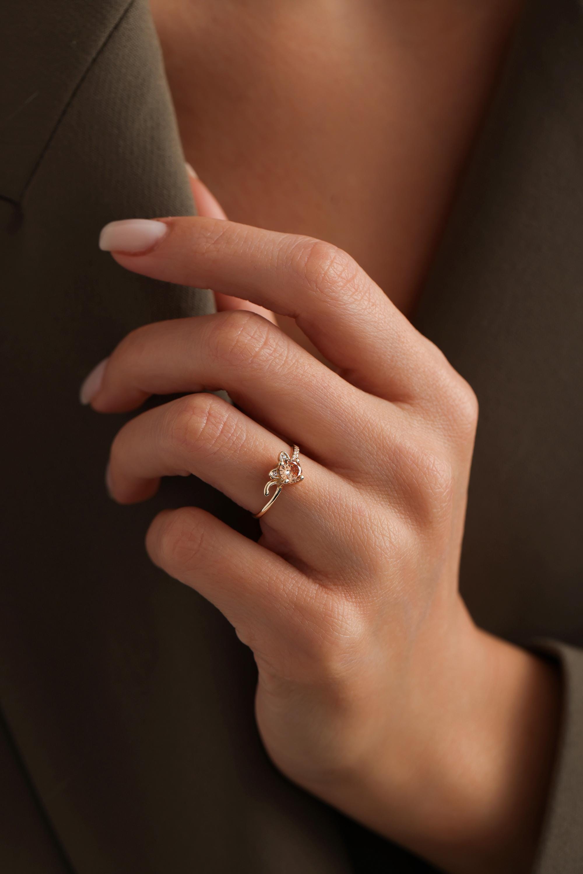 A close-up of a person's hand wearing a gold ring with a floral design.