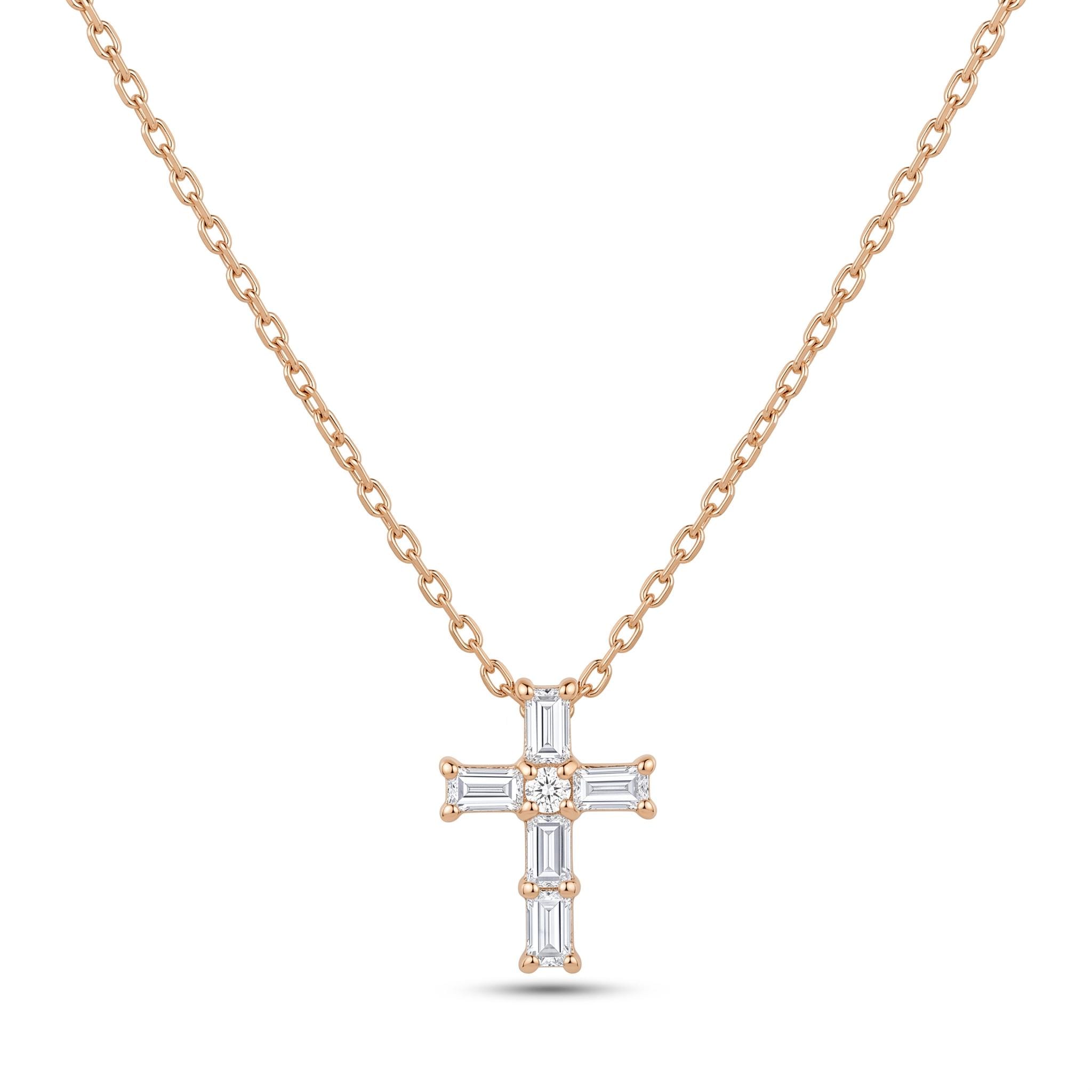 A delicate gold-colored necklace with a small, intricately designed cross pendant featuring a diamond center stone surrounded by smaller diamonds.