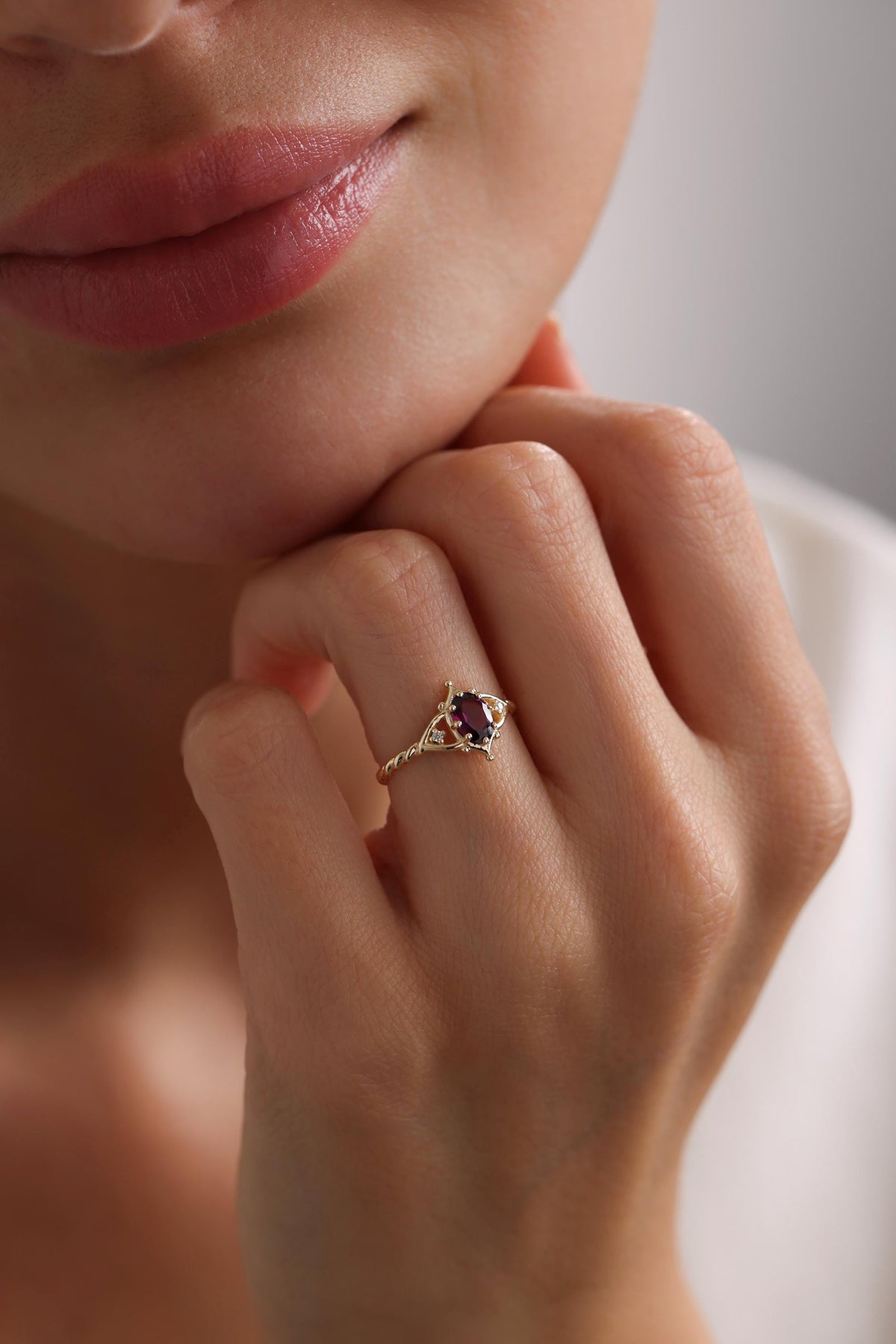 May include: A gold ring with a purple oval gemstone surrounded by smaller clear gemstones. The ring has a twisted band.