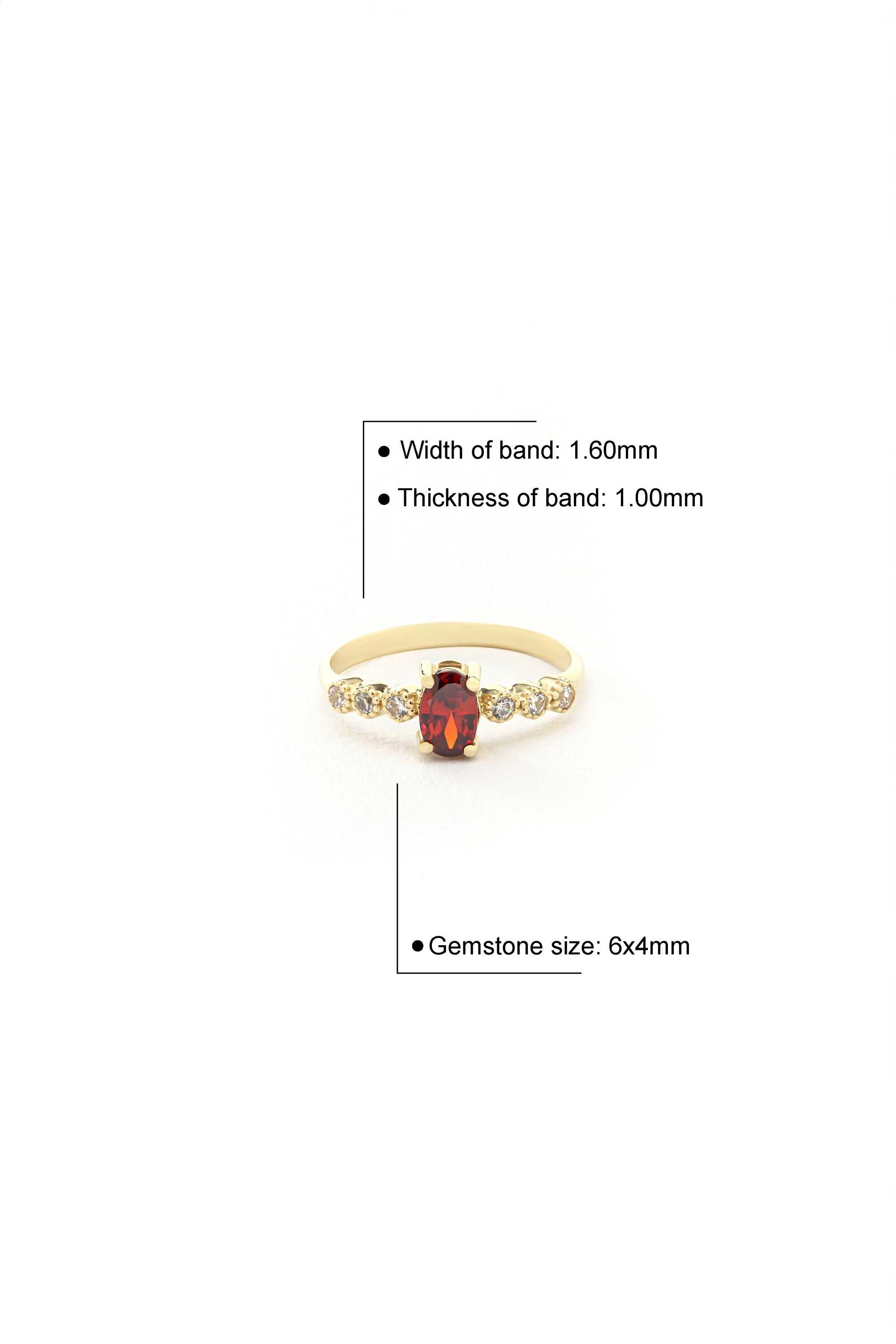 A gold ring with a red gemstone set in the center, along with a detailed size chart indicating the width of the band, thickness of the band, and the size of the gemstone.